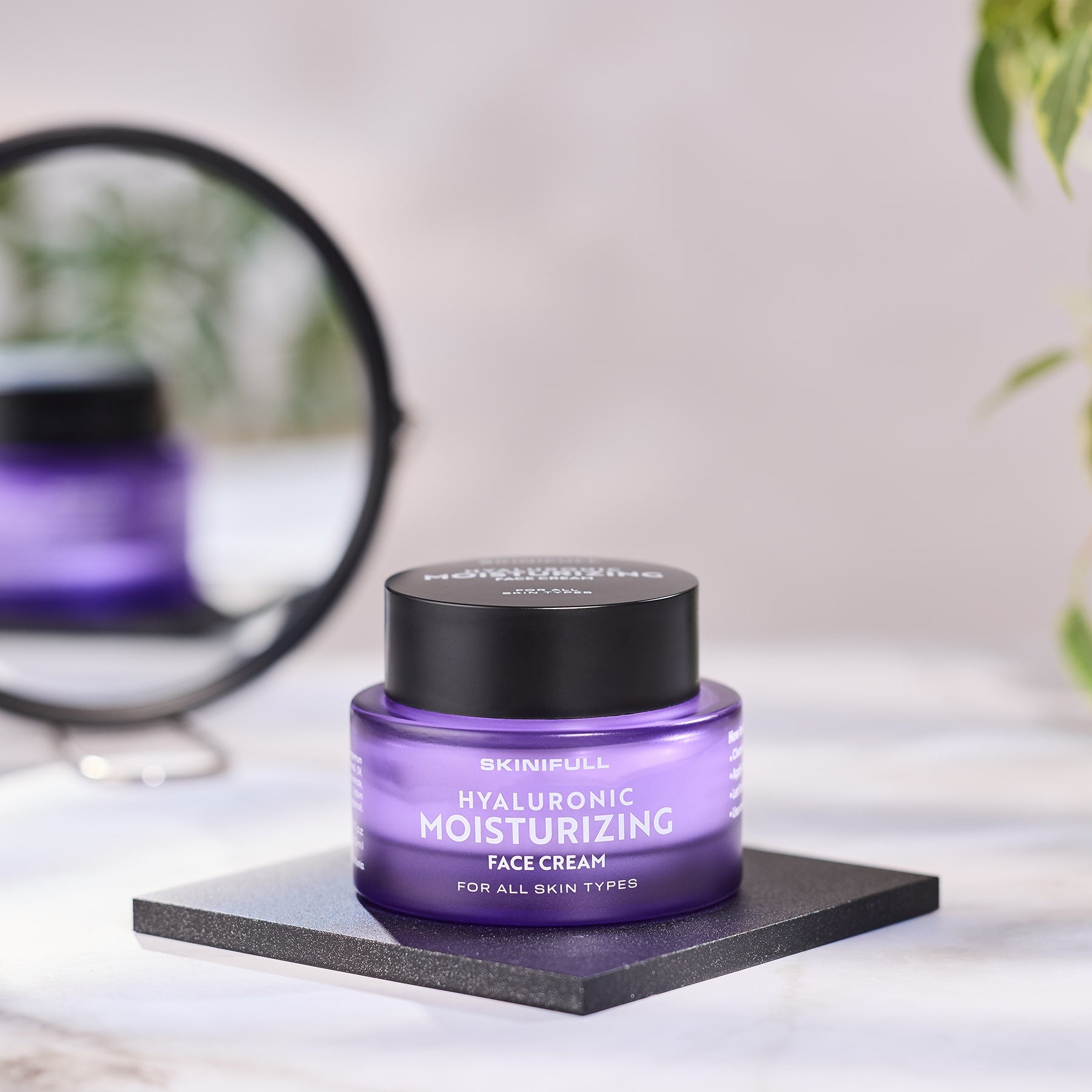 Skinifull Hyaluronic Moisturizing Face Cream stiklainėlis padėtas ant stalelio šalia veidrodžio