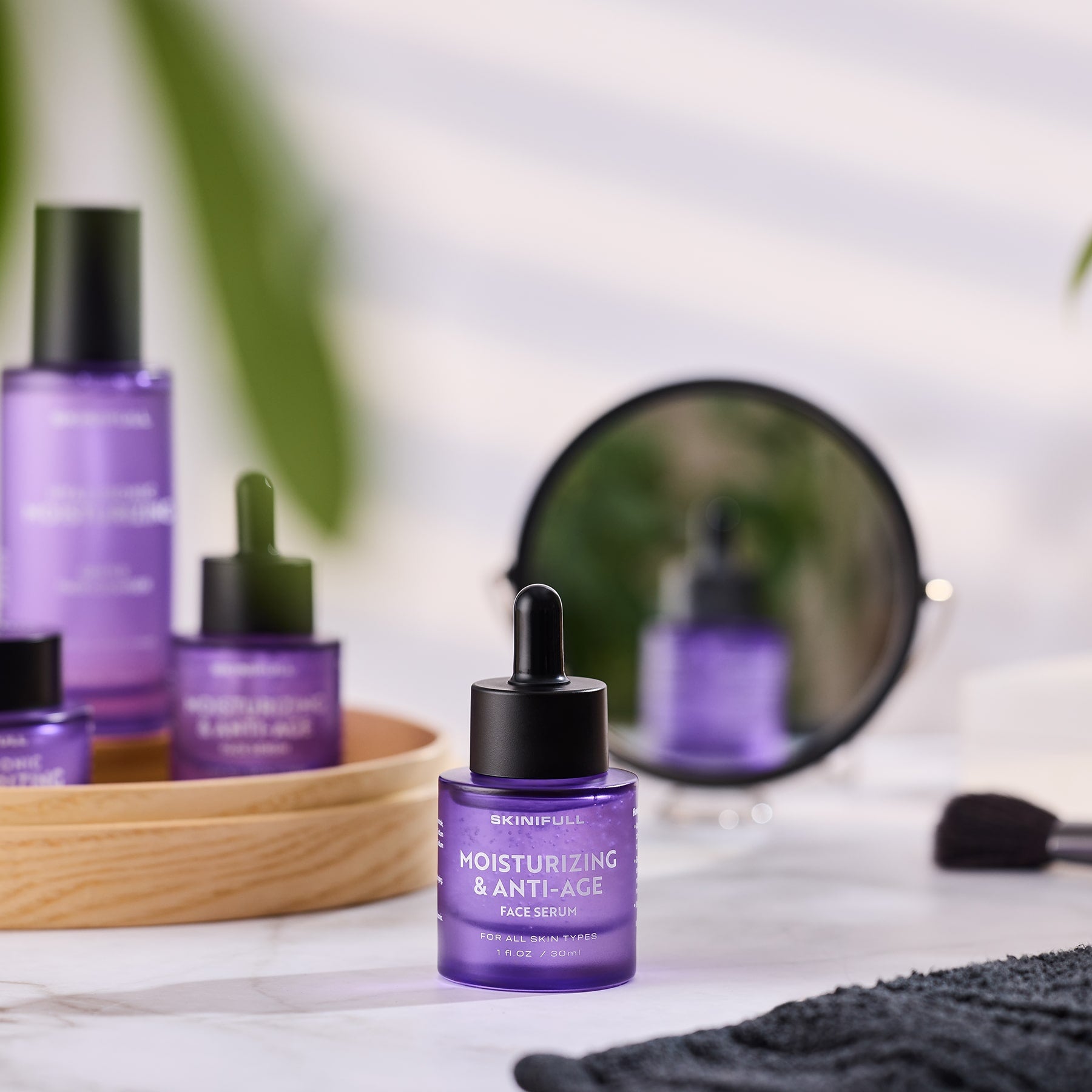 Skinifull Moisturizing & Anti-Age Face Serum buteliukas ant stalelio prie veidrodžio, šalia kitų Skinifull produktų
