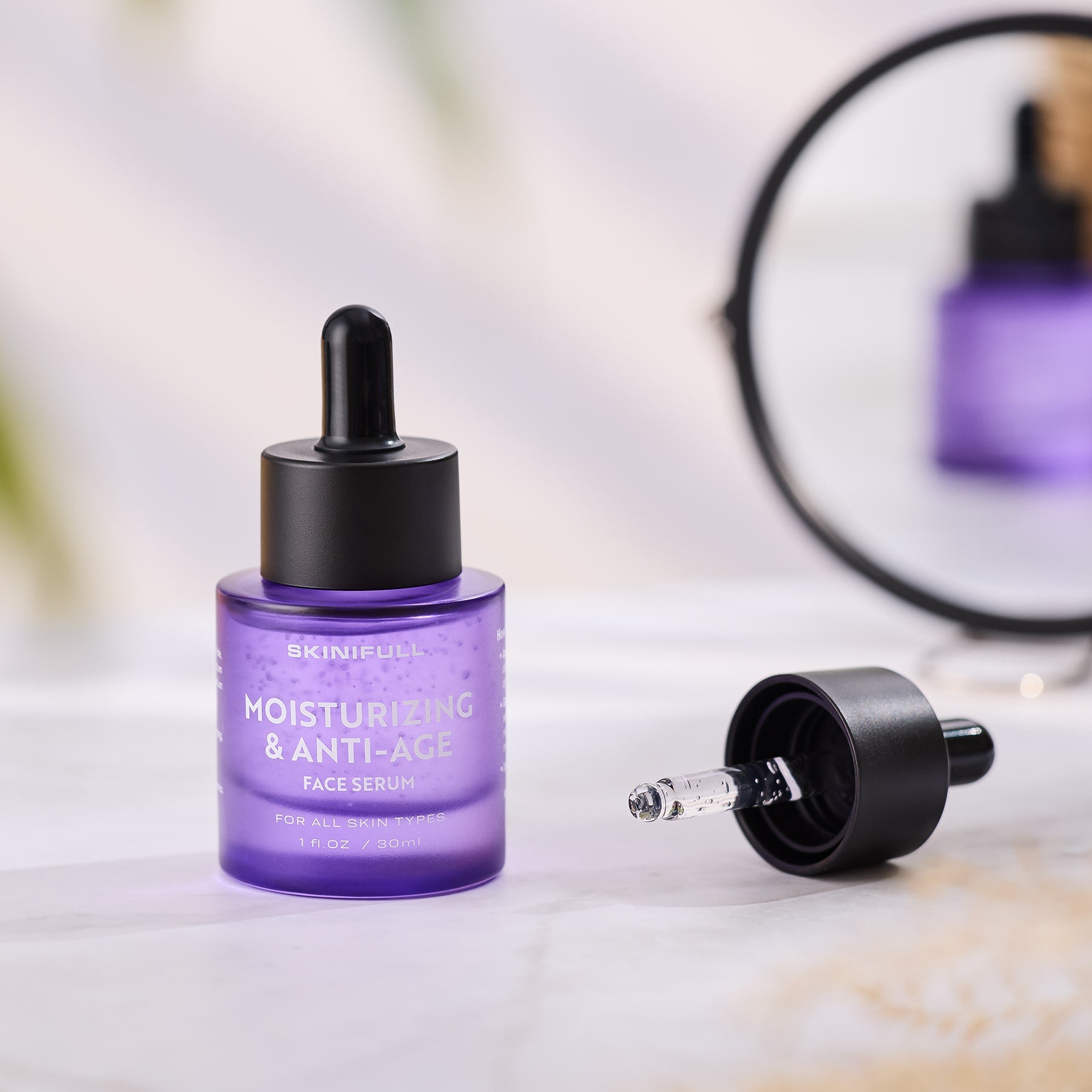 Skinifull Moisturizing & Anti-Age Face Serum – violetinis buteliukas su atidaryta pipete, padėtas prie veidrodžio